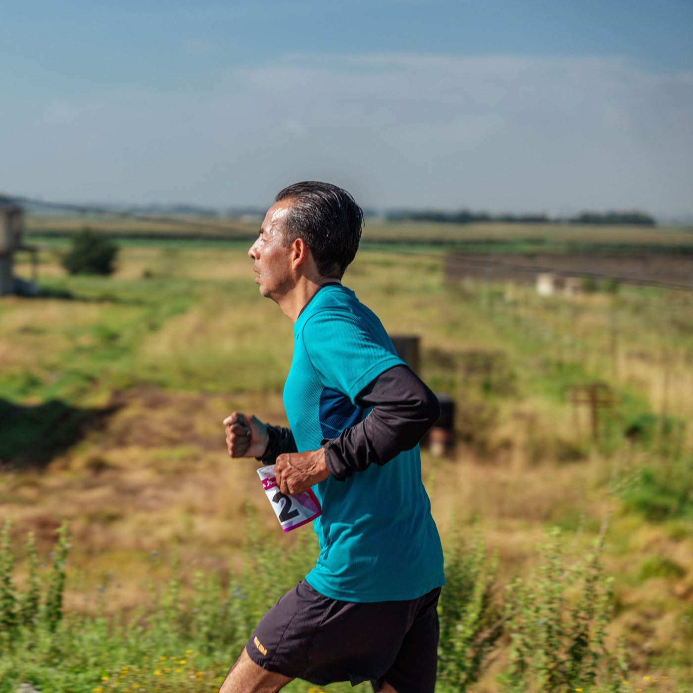 Gray-haired man running through a sunlit field