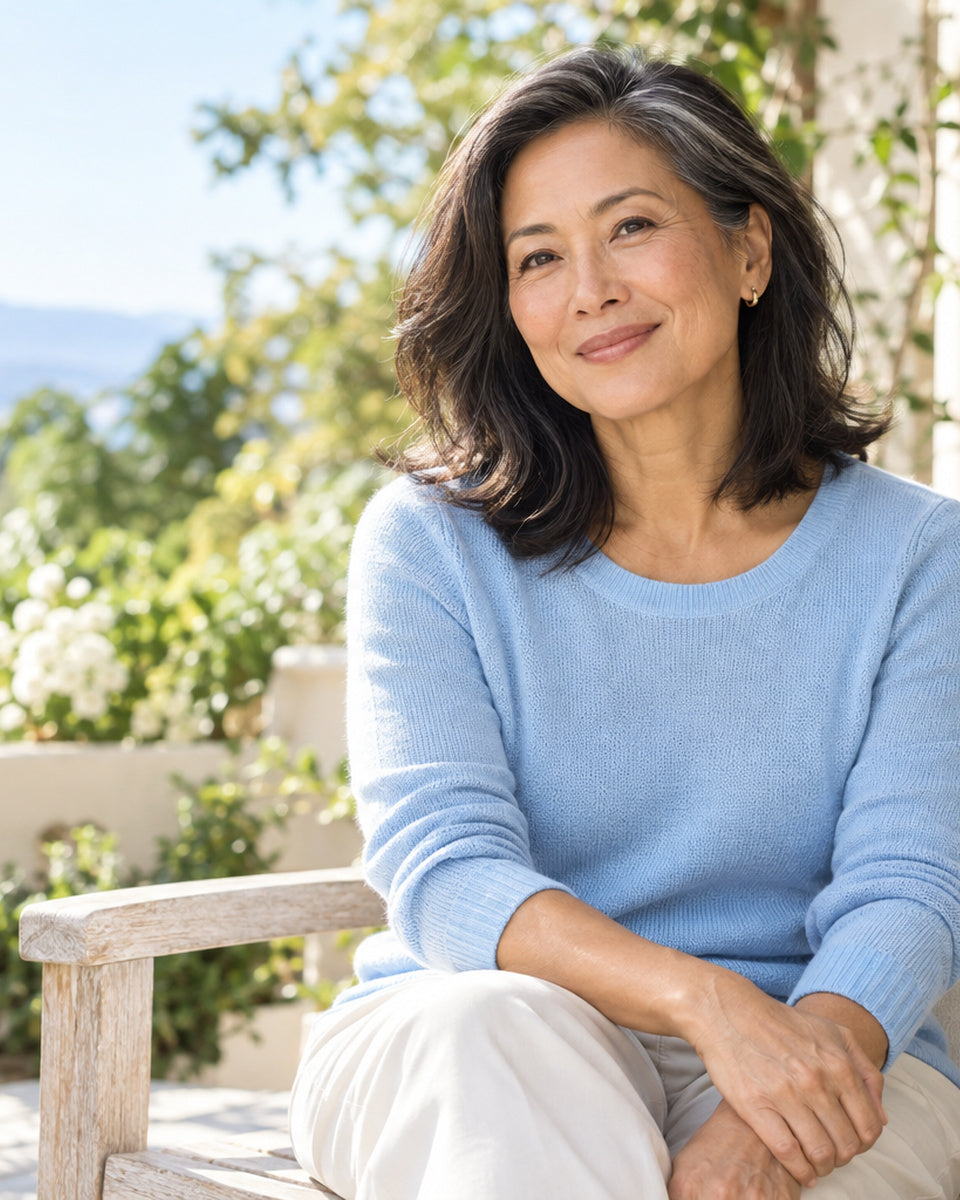 Smiling woman with her eyes closed, applying cream to her cheek